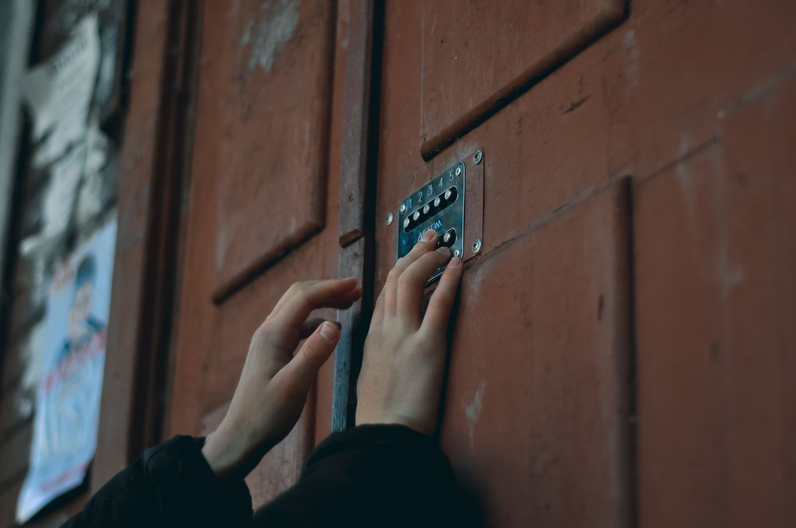 Handen voeren een code in op een toetsenpanelslot op een houten deur